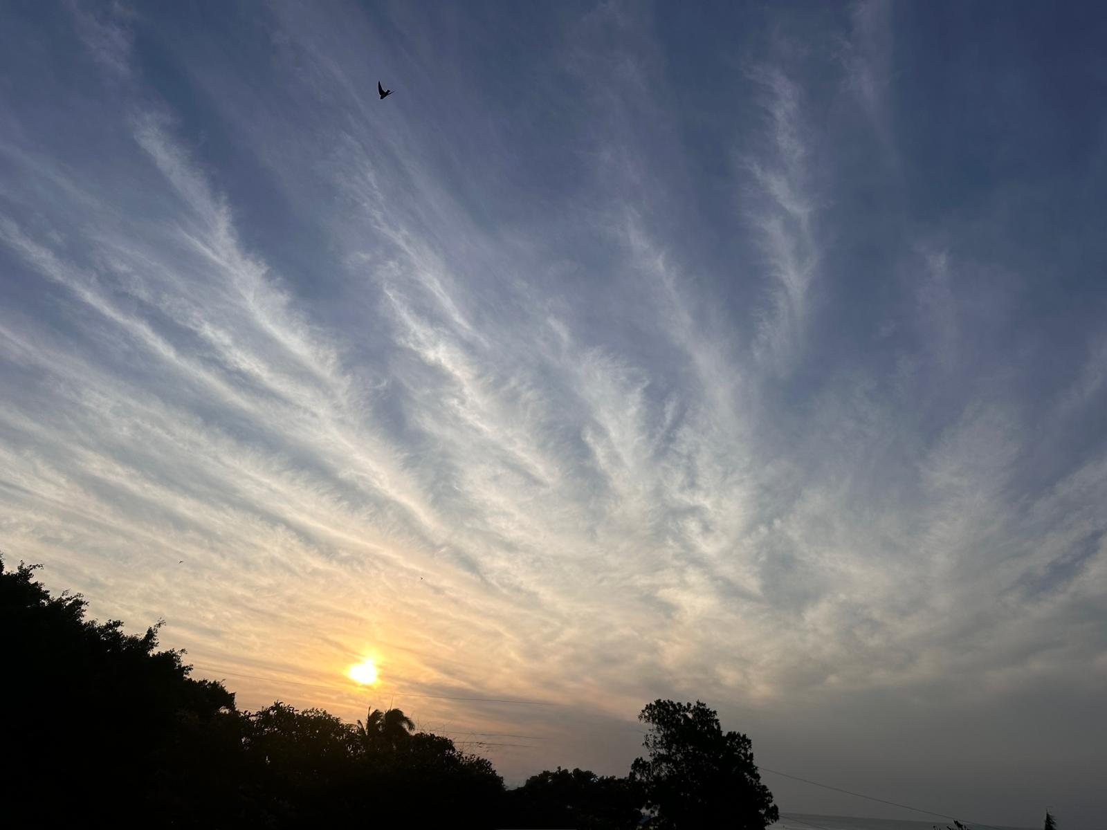 The sun sets behind the clouds